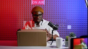 African american tech blogger with cameras opening box and recording video review of new smartphone