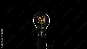 Real Edison light bulb flickering. Vintage filament Edison light bulb. Close up. 4K UHD video. Symbol of idea. The light comes on on a black background.