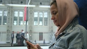 Beautiful European girl smiling happily, using smartphone social network app and looking around on train window seat.