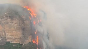 Fire drips down a clifftop in the Blue Mountains into a valley