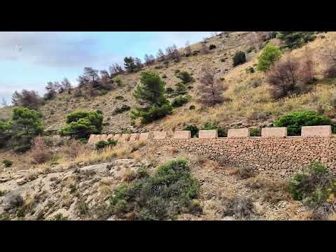 A stunning hillside landscape with a stone wall and a serene view