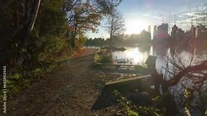 Path and View of Lost Lagoon. Famous Stanley Park. Sunny Fall Morning. Modern city with buildings skyline in background. Colorful Sunrise. Downtown Vancouver, British Columbia, Canada. Slow Motion