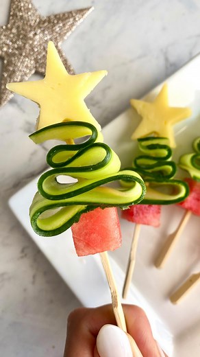 Christmas tree skewers 🎄 Get into the holiday spirit with a twist – cucumber Christmas trees that are as refreshing as they are festive! Ingredients Cucumber Cheese Watermelon Salt Wooden skewers 1. Slice your cucumber lengthwise using a vegetable peeler 2. Sprinkle cucumber slices with a pinch of salt 3. Cut watermelon into cubes 4. Use a star-shaped cutter to cut cheese into star shapes 5. To assemble: to your skewer add watermelon cube. Weave cucumber ribbon into the shape of a tree, top wit