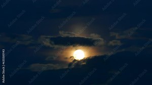 Dark blue evening sky with slowly moving clouds and full moon with orange light around - real time. Topics: cosmos, astronomical observation, earth satellite, nature, weather