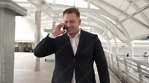 Skilled businessman receive good news for getting promotion while walking to workplace. Happy smart manager calling or talking to telephone with marketing team for increasing sales. Lifestyle. Urbane.
