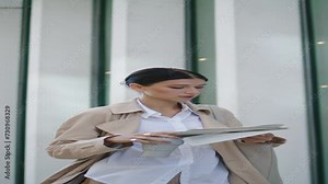 Businesswoman walking reading newspaper on street. Girl holding press vertically