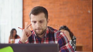 tired Young man sitting opposite the computer. Long working day. in the background, people are crowded. 4k