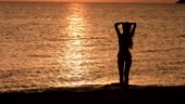 Junge sportliche Frau am Strand bei Sonnenuntergang