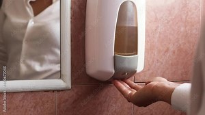 Woman Washing hands with soap how to wash - squirt liquid from soap wall dispenser