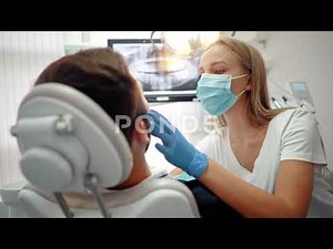 female dentist in blue latex gloves examines patient's teeth