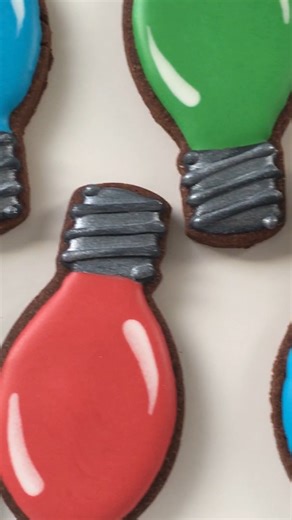 These Christmas lights cookies remind me of the lights we had when I was growing up! The Christmas light bulb cookie cutter and the bow cookie cutter are both from Ann Clark Cookie Cutters. My chocolate cookie recipe and royal icing recipe are available to members of the Cookie Art Club! #christmastradition #christmastreats | SweetAmbs