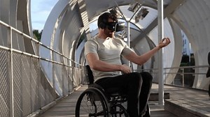Middle-aged man in a wheelchair explores virtual environments using VR headset in a contemporary urban setting. Man in Wheelchair Experiencing Virtual Reality on City Bridge