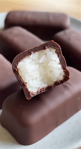 Indulge in these homemade dark chocolate Mounds bars featuring a chewy, snowy coconut center and a snappy dark chocolate shell! 🥥🍫 🛒 Ingredients : 3 cups Sweetened shredded coconut 3/4 cup Sweetened condensed milk 1/2 teaspoon Vanilla extract 1/8 teaspoon Salt 2 cups Dark chocolate chips or melting wafers 1 tablespoon Coconut oil 👩‍🍳 Easy Steps : 🥣 The Coconut Base In a large glass bowl, combine the shredded coconut, sweetened condensed milk, vanilla, and salt. Stir thoroughly with a spatu