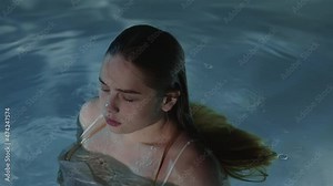 A girl with red hair in slow motion emerged from the water