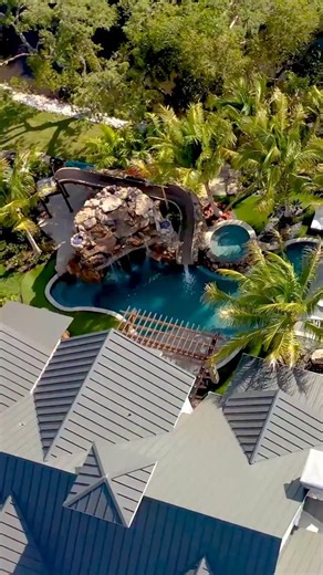 This backyard has an amazing slide, natural rock grotto, sunken fire pit, spa, putting green, and beautiful landscaping. What do you think of this backyard? #insanepools #lucaslagoons #poolbuilding #waterslide | Lucas Lagoons