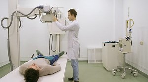 Young male doctor using xray machine to examine patient