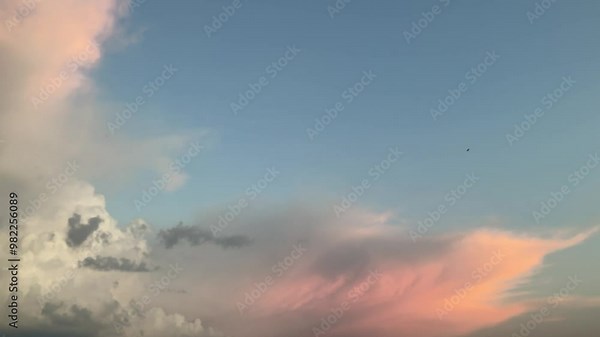 Blue sky with stormy menacing Anvil cloud, Cumulonimbus incus illuminated in orange by sunlight at the evening - shot with camera movement. Topics: storm alert, meteorology, weather, nature, climate