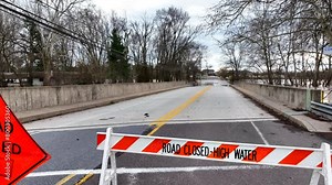 Road closed - high water sign at bridge with flooding. Aerial reveal. Natural disaster theme.