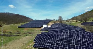 Flying over a solar panel , solar farm with photovoltaic, solar panels converting solar power to electricity for green energy on agricultural land