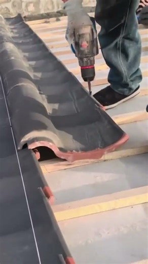 installing roof tiles using power drill and fixing clay shingles for house construction project
