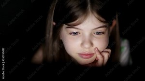 a little girl uses a laptop at night, plays games, watches videos, communicates with friends on social networks, children's addiction to gadgets, concept