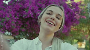Young happy girl video call with her smartphone near a flowering tree.Technology use. Woman's perspective. Camera view.
