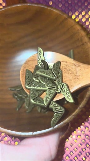 Small golden patinated book corners gently stirred in a wooden mug with a dark wooden spoon 🪵✨