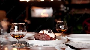 Romantic dinner scene with two glasses of dessert liquor and a pastry to share with a fire burning in the background