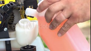 Refueling off petrol lawn grass weed trimmer with internal combustion engine and manual starter.