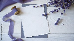 White blank card, envelope and ribbon on a background of pink and blue fabric with lavender flowers on a white background. Mockup with envelope and blank card. Flat lay. Top view