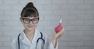 Child with enema. A smiling child play with an enema like a nurse in the room.