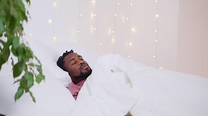 wake up in early morning, black man lying in bed, opening eyes and rising, daily routine and rest