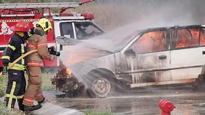 Asian fireman wear fire protection suit. Firefighter fighting with fire on a car during fire drill Traffic Accident at Fire station Concept. Slow motion