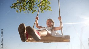 little girl kid swinging on a wooden swing on a tree in the park. happy family kid dream concept. little kid girl playing on wooden swing fun on tree dream concept in park