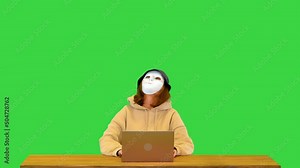 Hacker girl in anonymous mask and hoodie typing on laptop coding virus software for fraud attack on a Green Screen, Chroma Key. Stock Video