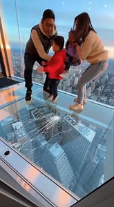 Glass Floor Cracks Beneath Family as Observation Deck Visit Turns Into Panic Chicago, IL — A family’s visit to a popular skyscraper observation deck turned into a moment of sheer terror when the glass floor beneath them suddenly appeared to crack, sending spiderweb fractures racing outward as they stood hundreds of feet above the city. The video shows two adults and two small children standing inside a glass viewing box, the skyline visible far below their feet. As the family shifts their weight