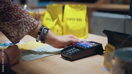 Woman paying with credit card at coffee shop counter using contactless pos terminal technology