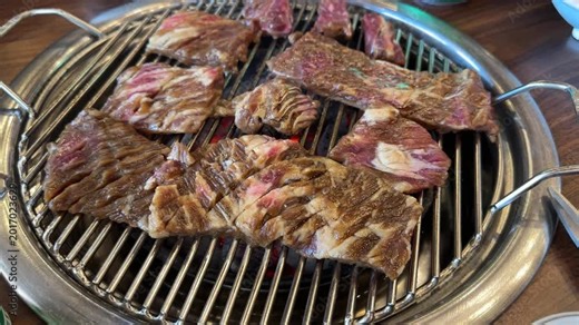 Grilling meat at a Korean barbecue restaurant in downtown area with friends during evening hours