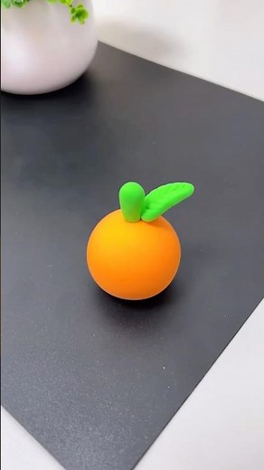 A delightful miniature orange crafted from clay, complete with a vibrant green stem and leaf! 🍊🌿✨