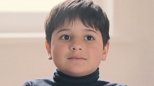 The boy looks at the camera with enthusiasm and surprise