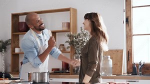 Video of lovely attractive couple dancing while cooking in the kitchen at home