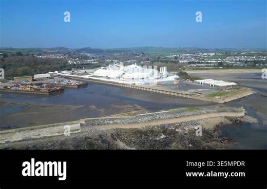 Par, Cornwall, England: DRONE VIEWS: Par Docks with the town of Par and Par Sands beach in the background. The Docks is a milling centre and also receives a slurry form of china clay for transporting to nearby Fowey Stock Video Footage - Alamy