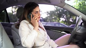 Woman in car talking on mobile phone whilst driving. Beautiful girl driver uses smart phone while traffic jam in city center.