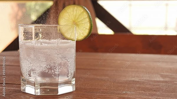 Bubbles rise and pop in glass of sparkling water, creating a refreshing and lively scene. Each bubble bursts with energy, highlighting the effervescence of drink as bubble activity continues.