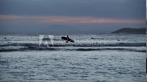 Surfer with a surfboard goes to sea. The surf line. Surfers lying on boards floating on the waves