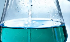 Liquid Alchemy: Close-up macro shot of a beaker being filled with a vibrant teal liquid, water droplets clinging to the glass, creating a mesmerizing visual of scientific exploration and discovery.