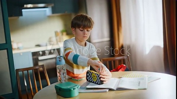 Boy packing school backpack home kitchen. Serious preteen child organizing