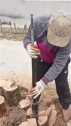 worker uses a heavy slide hammer to split wood