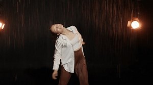 Dancing in the rain. A young woman in wet clothes dancing among water droplets, aqua studio. beautiful silhouette, model in a white shirt