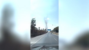 Towering dust devil tornado spins along roadside